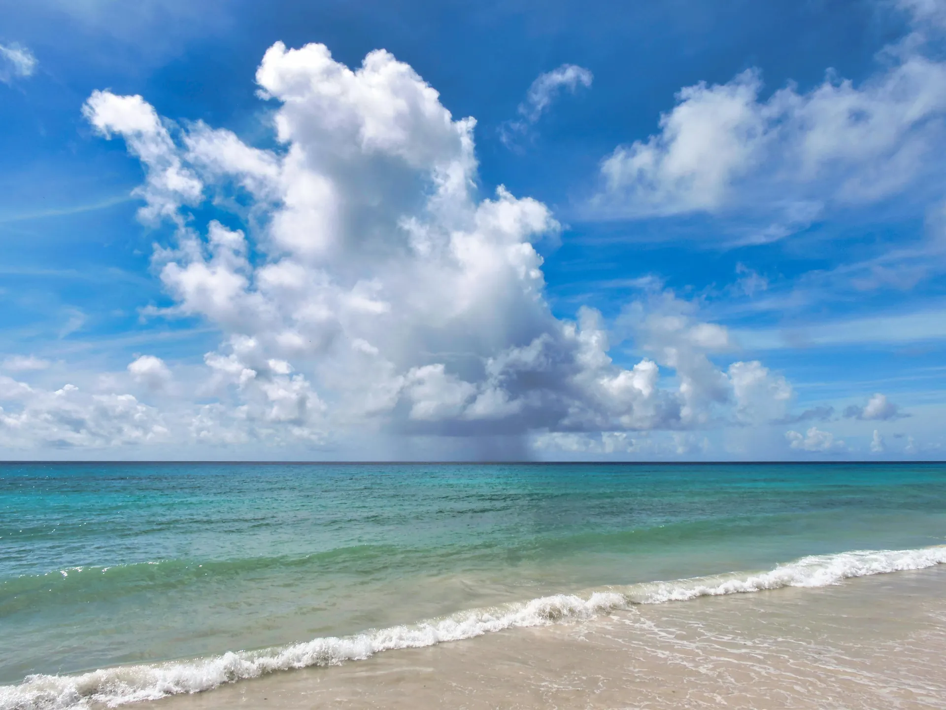 Tranquil ocean scene with dramatic clouds and clear blue water at a Barbados beach.
