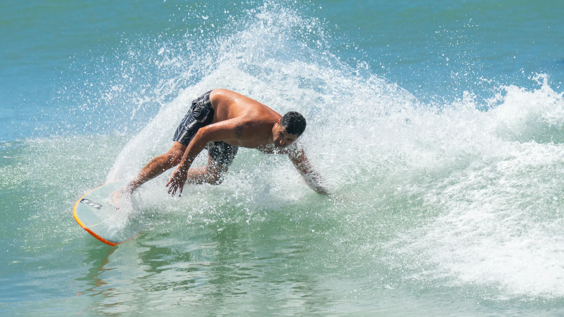 A surfer skillfully maneuvers on a wave, creating a dramatic splash.
